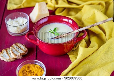 Cheese Cream Soup On A Red Wooden Background. White Bread Croutons. Ingredients.