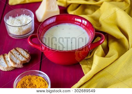 Cheese Cream Soup On A Red Wooden Background. White Bread Croutons. Ingredients.