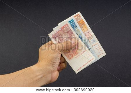 Hand Holding Fifty Croatian Kuna Or Sto Kuna Bank Notes On Black Background. Financial Concept And S