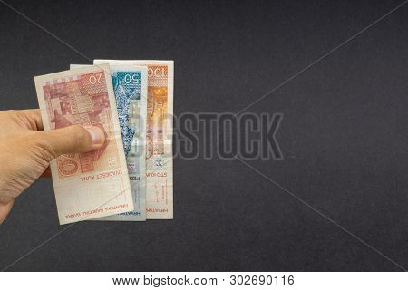 Hand Holding Fifty Croatian Kuna Or Sto Kuna Bank Notes On Black Background. Financial Concept And S