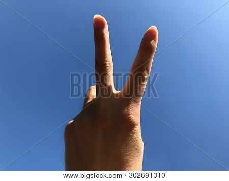 Two Fingers Up On A Blue Background