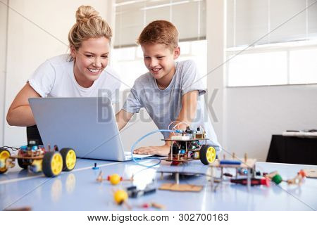 Male Student With Teacher Building Robot Vehicle In After School Computer Coding Class