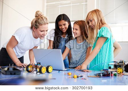 Three Female Students With Teacher Building Robot Vehicle In After School Computer Coding Class