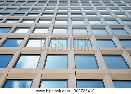 New office building in business center. Wall made of steel and glass with blue sky.