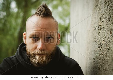 Serious Or Calm Young Bearded Man Sitting In Front Of The Camera