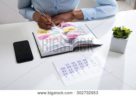 Businesswoman's Hand Checking Schedule In Diary