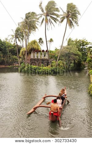 A Man Guiding A Canoe Boat On A Small Stream At The Polynesian Cultural Center, A Polular Attraction