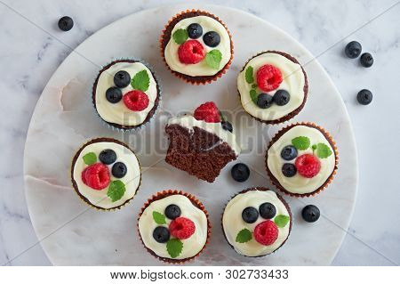 Chocolate Muffins Or Cupcakes With Whipped Cream And Berries, Flat Lay On White Marmor Stone Backgro