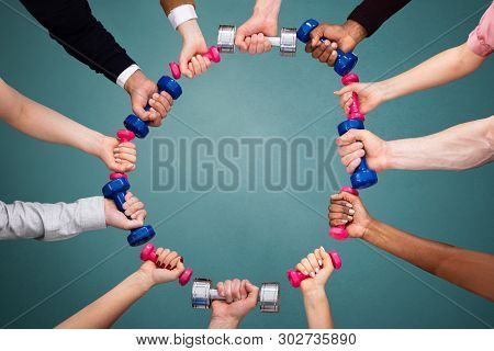 People's Hand Making Circular Shape With Colorful Dumbbells