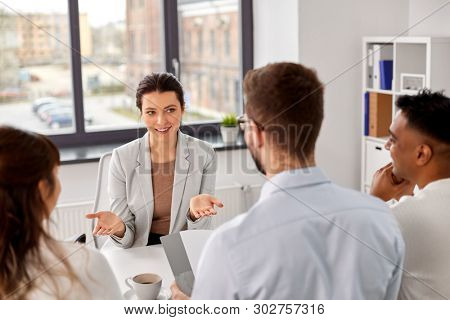 new job, hiring and employment concept - international team of recruiters having interview with female employee at office