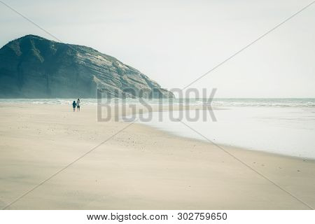 A Couple Walking Hand In Hand Exploring Wharariki Beach. Wharariki Beach Is West Of Cape Farewell, T
