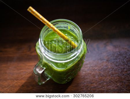 jar with green cold-pressed juice, wooden background. Healthy eating, detoxing, juicing body cleancing concept 