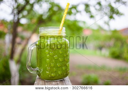  a jar with green cold-pressed juice, nature background. Healthy eating, detoxing, juicing, body cleancing concept 