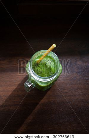 jar with green cold-pressed juice, wooden background. Healthy eating, detoxing, juicing body cleancing concept 