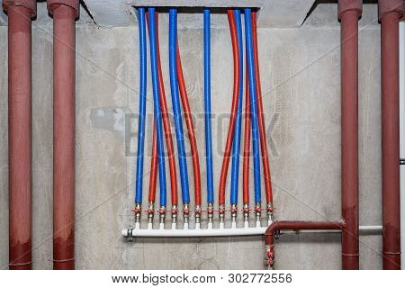 Pipes Of Heating And Water Supply System On The Background Of A Concrete Wall.