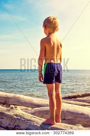 Toned Photo Of A Little Kid Stand On The Log On The Sea Background