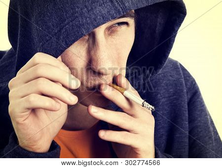 Toned Photo Of Young Man In A Hoodie With A Cigarette Closeup