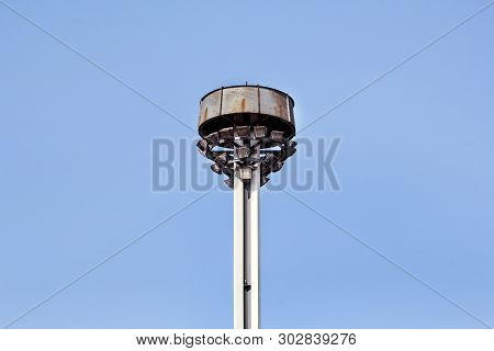 Tower With Reflectors At The Roundabout On The City Road And Street. Lighting Pole With Blue Sky. Bi