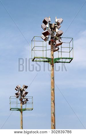 Stadium Floodlight Tower With Reflectors With Blue Sky. Lighting Pole Tower At The Sports Stadium An