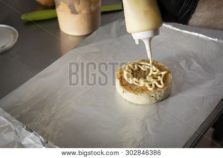 Chef Putting Mayonnaise On Hamburger Bread With Buttle