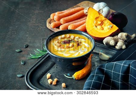 Spicy Pumpkin And Carrot Soup With Ginger, Garlic, Red Onion And Chili On Dark Background. The Soup 
