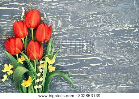 Bunch Of Red Tulips, Daffodils And Lily Of The Valley Flowers On Rustic Background. Space For Your T