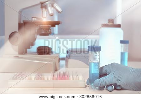 Scientific Background With Microscope Room. Shallow Dow, Toned Image. Focus Here Is On Gloved Hand.