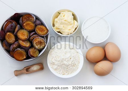 Ingredients For Plum Pie Baking On A White Background: Butter, Flour, Sugar, Baking Powder, Eggs, Fr