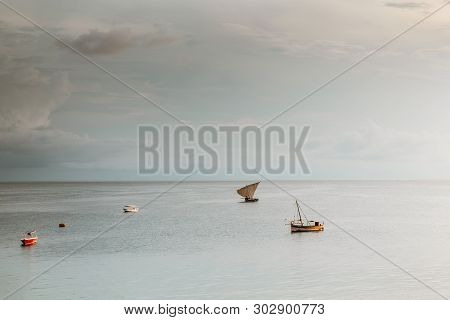 Ancient Old Sailing Boat In The Ocean Goes Downwind At Sunset Against A Cloudy Sky