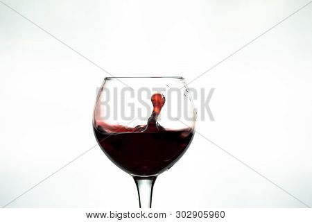 Red Wine Splash Into Glass On White Background.