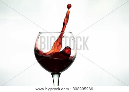 Red Wine Splash Into Glass On White Background.