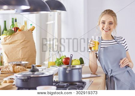 The Girl At The Table In The Kitchen With A Glass Of Orange Jui