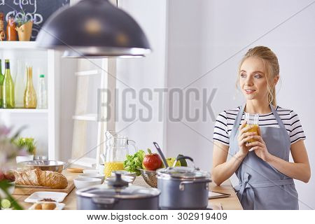 The Girl At The Table In The Kitchen With A Glass Of Orange Jui