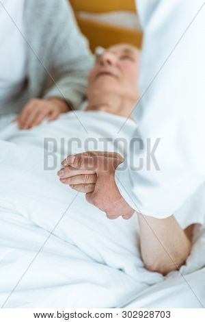Cropped View Of Doctor Standing Near Patient In Coma And Holding His Hand