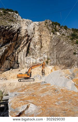 Orange Tracked Excavator With The Jackhammer In A Quarry, Carrara White Marble In The Apuan Alps (al