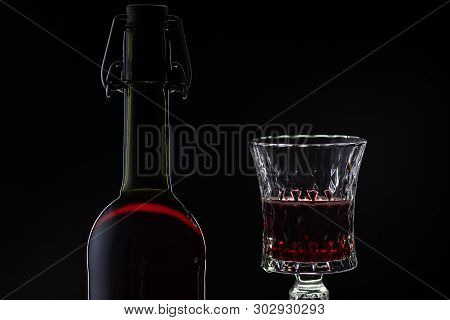 Wine. Red Wine In Wine Glass Over Dark Background. Silhouette Of Bottle With Rose Wine And Opener On