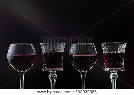 Rose Wine. Red Wine In Four Wine Glasses Over Dark Background With Rays Of Light.