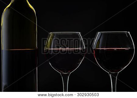 Wine. Red Wine In Two Wine Glasses Over Dark Background. Silhouette Of Bottle With Rose Wine