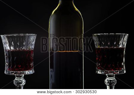 Wine. Red Wine In Two Wine Glasses Over Dark Background. Silhouette Of Bottle With Rose Wine