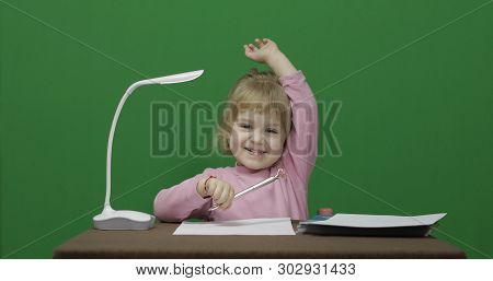 Girl At The Table. Education Process. Raises Her Hand Because She Knows The Answer To The Question. 