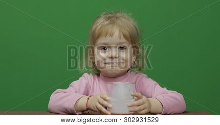 Girl Sitting At The Table And Drinks Yogurt Milk. Funny Milk Mustache. Happy Three Years Old Girl. P