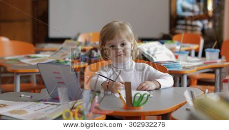 Girl Drawing At The Table In Classroom. Education Process. Happy Three Years Old Child Sitting At A 