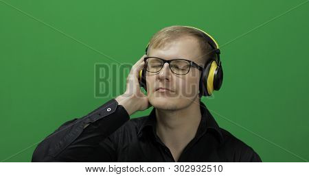 Guy Listens To Energetic Music In Wireless Yellow Headphones And Dances. Portrait Of Attractive Man 