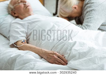 Selective Focus Of Sad Senior Woman With Husband In Coma In Clinic