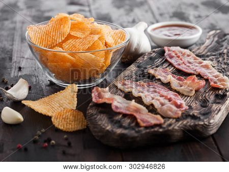 Potato Crisps With Backon Flavour With Grilled Bacon Rashers On Vintage Chopping Board With Garlic A