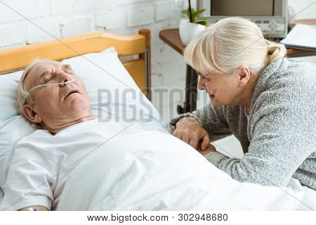 Sad Senior Woman With Husband In Coma In Hospital