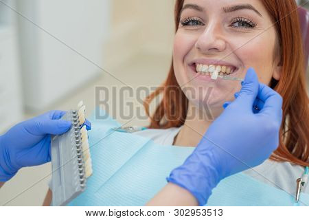 Check And Select The Color Of The Teeth In The Dentist Chair. Dentist Makes The Process Of Treating 