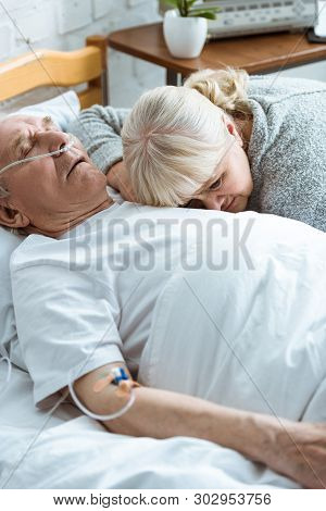 Sad Senior Woman With Husband In Coma In Clinic