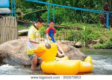 Two Boy Prepare To Jump On Plastic Duck Balloon To Row Downstream