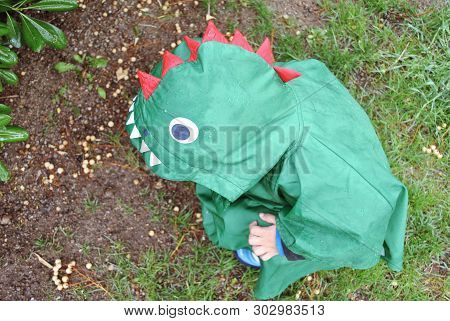 Portrait Child In Monter Raincoat Playing With Snails.